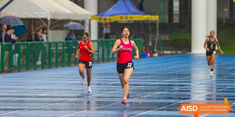 Concordia International School Shanghai students running a race on a wet red track during a track and field event.