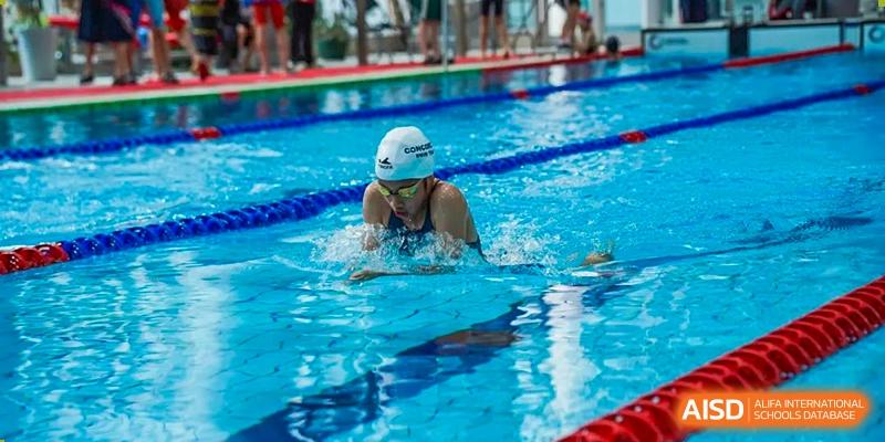 A Concordia International School Shanghai student swimming laps during a competition or practice in an outdoor pool.