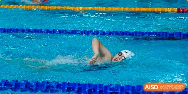A competitive swimmer from Concordia International School Shanghai performing the butterfly stroke in a pool.