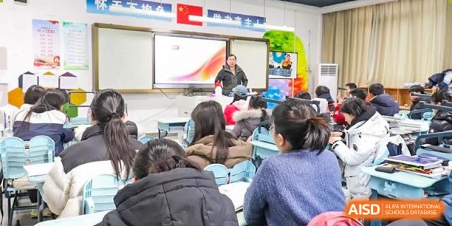 A male teacher giving a lecture to a full class, with the presentation displayed on the large screen at the Hefei No.1 High School.