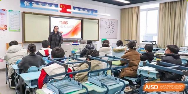 A female teacher addressing the class in a brightly lit classroom equipped with smart board technology at the Hefei No.1 High School.