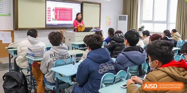 A teacher giving a presentation to students seated in a classroom, focusing on the back row at the  Hefei No.1 High School.