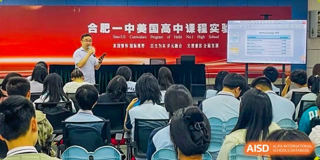 Students attending a large lecture or seminar under a red banner displaying the school program name at the  Hefei No.1 High School.