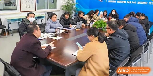 A group of teachers and administrators are gathered around a large wooden table for a meeting or discussion at the  Hefei No.1 High School.