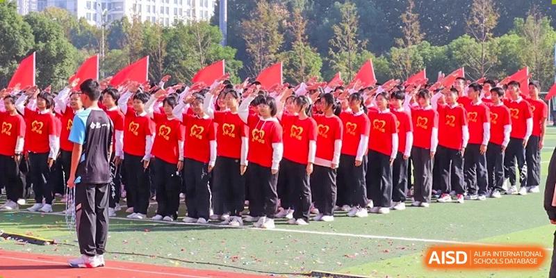 A large group of students in red uniforms standing in formation on a field during a ceremony or sports day at the Hefei No.1 High School.