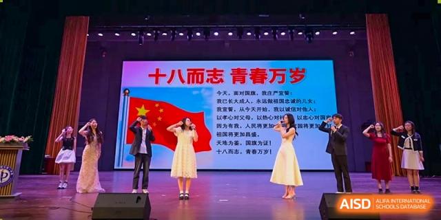 Students performing on a stage with a Chinese display banner and a flag during a cultural event at the Hefei No.1 High School.
