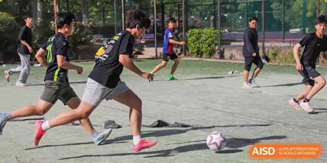 A student dribbling a soccer ball during an intense football match on a sports field at the Hefei No.1 High School.