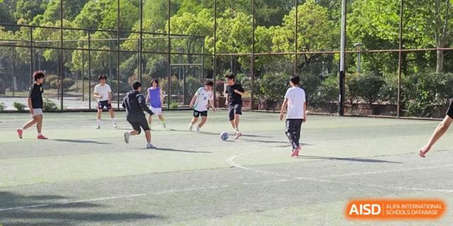Students engaging in a game of football or soccer on the outdoor playing field at the Hefei No.1 High School.