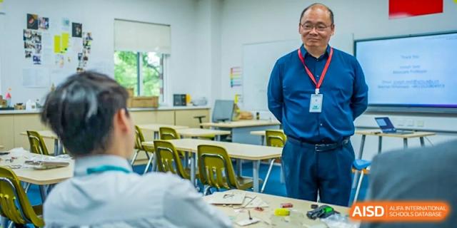 An adult instructor or teacher demonstrating a hands-on activity in a science or workshop classroom at Hiba Academy Hangzhou.