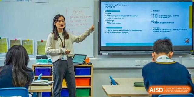 A female teacher pointing to information on a large digital screen while teaching a class at Hiba Academy Hangzhou.