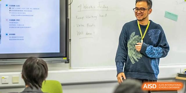 An adult writing notes about the day's class topic on a whiteboard while a student watches in the classroom at Hiba Academy Hangzhou.