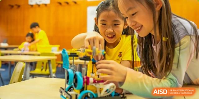 Young students collaborating on building a robotics project or structure at Hiba Academy Hangzhou.