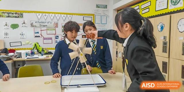 Students working together to build a model structure out of materials like wooden skewers and marshmallows during a science challenge at Hiba Academy Hangzhou.