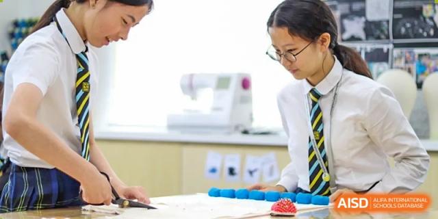 A female student in uniform observing a setup or activity in a science or technology classroom at Hiba Academy Hangzhou.