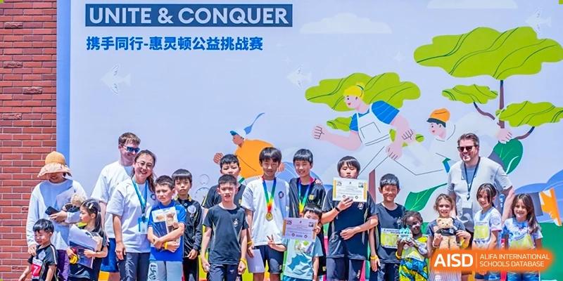 A group of students posing in front of an event banner that reads "CONQUER" and features colorful illustrations, likely from a challenge or competition at Hiba Academy Hangzhou.
