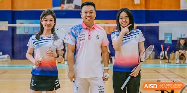 An adult and a student posing with badminton rackets in a sports facility at Hiba Academy Hangzhou.