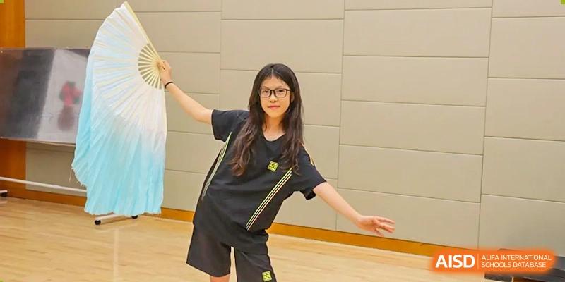 A female student in a black and yellow sports uniform posing indoors at Hiba Academy Hangzhou.