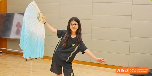 A female student in a black and yellow sports uniform posing indoors at Hiba Academy Hangzhou.