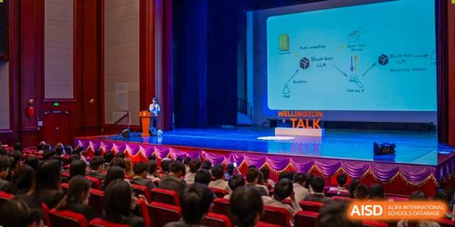 An audience watching a speaker give a "TALK" presentation on a large screen on a stage in the school auditorium at Hiba Academy Hangzhou.