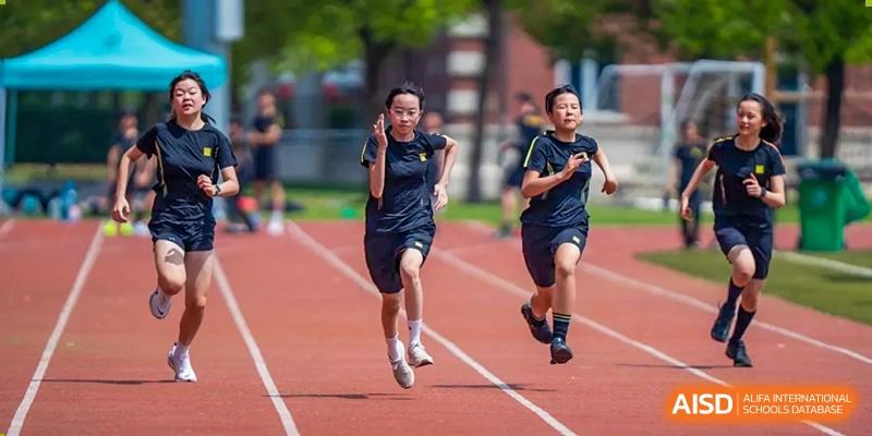 Two female students running a race on a red outdoor track during sports training at Hiba Academy Hangzhou.