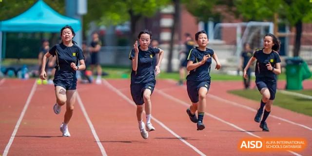 Two female students running a race on a red outdoor track during sports training at Hiba Academy Hangzhou.