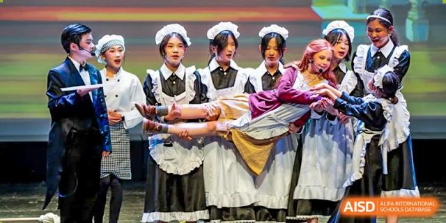 Students in maid and servant costumes performing a scene on stage for a school production at Hiba Academy Hangzhou.