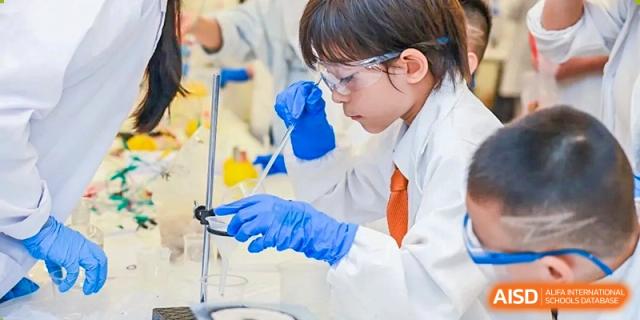 A close-up shot of a student in safety goggles and blue gloves carefully using a dropper during a lab experiment at Huitong School & Studios.