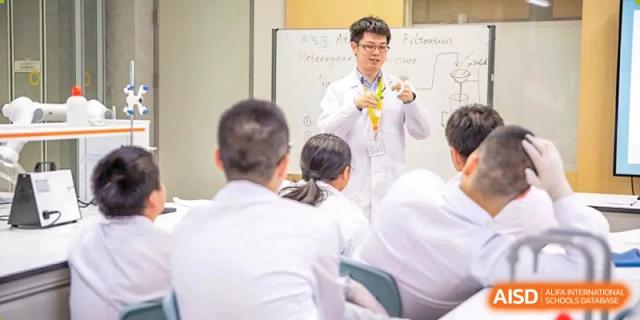 A teacher demonstrating a science experiment to a group of students in a classroom at Huitong School & Studios.