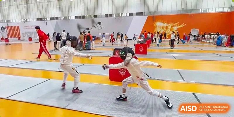 Two children in protective gear participating in a fencing lesson or match at Huitong School & Studios.
