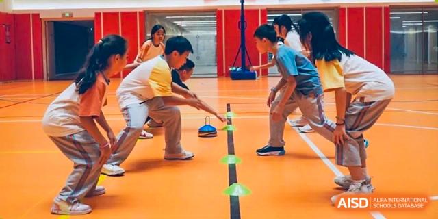 A group of children participating in an indoor sports activity, carefully balancing an object with a rope at Huitong School & Studios.