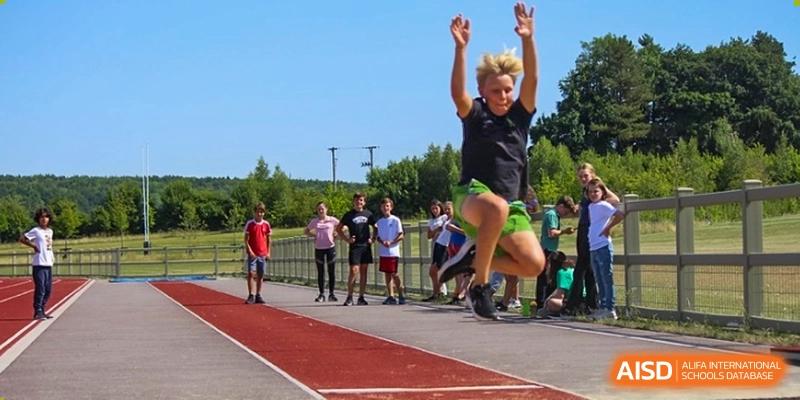 A student participating in a long jump or high jump event on an athletic track at Huitong School & Studios.