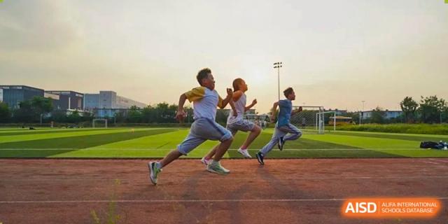 Students racing each other on a running track during an outdoor sports event at Huitong School & Studios.