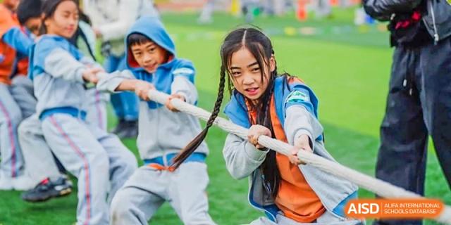 Two students playing a game of tug-of-war during a school activity at Huitong School & Studios.