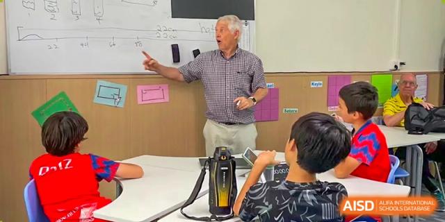 A teacher at QSI International School of Zhuhai instructs a student on using scientific equipment on a table.