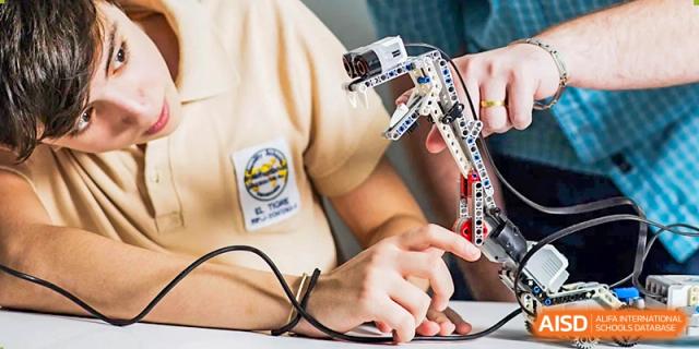 Close-up of a student's hands at QSI International School of Zhuhai assembling a small robotics or electronic device.