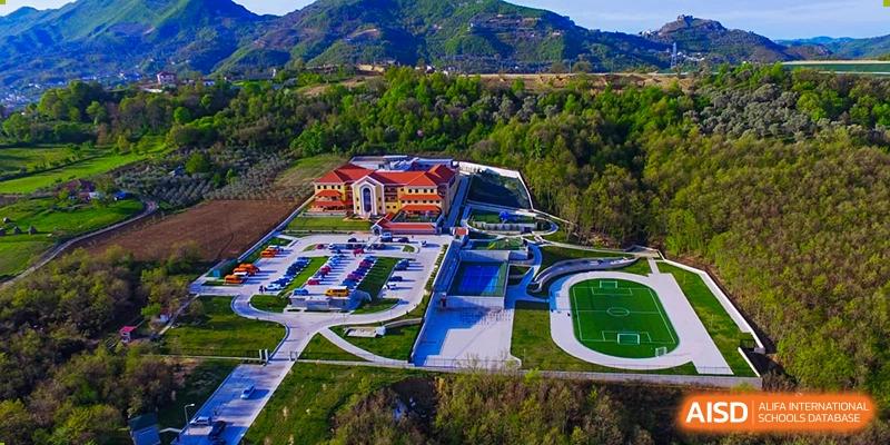 Aerial view of the QSI International School of Zhuhai campus showing the main building, surrounding green hills, sports track, and facilities.
