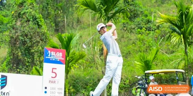 A student or staff member from QSI International School of Zhuhai is playing golf outdoors, mid-swing.