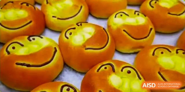 Close-up of baked goods decorated with cheerful, smiling faces, possibly served in the cafeteria or at an event at QSI International School of Zhuhai.