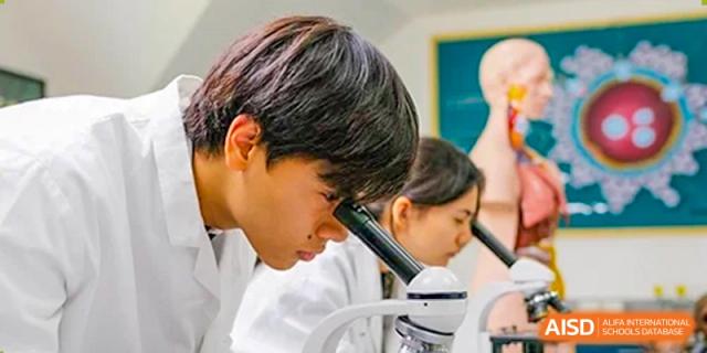 An image showing two students looking at a microscope in a laboratory at Wellington College International Shanghai.