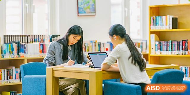 An image showing two students working on a laptop at a table at Wellington College International Shanghai.