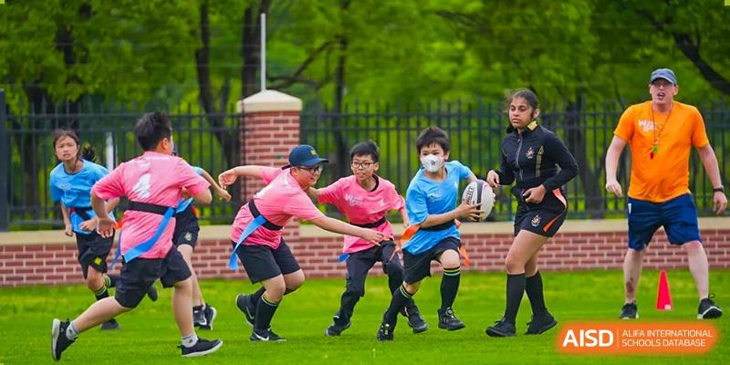 An image showing two boys playing with a rugby ball on a green field at Wellington College International Shanghai.