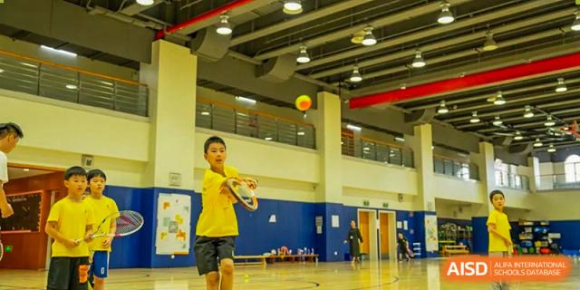 An image showing a young boy playing tennis inside a gymnasium at Wellington College International Shanghai.