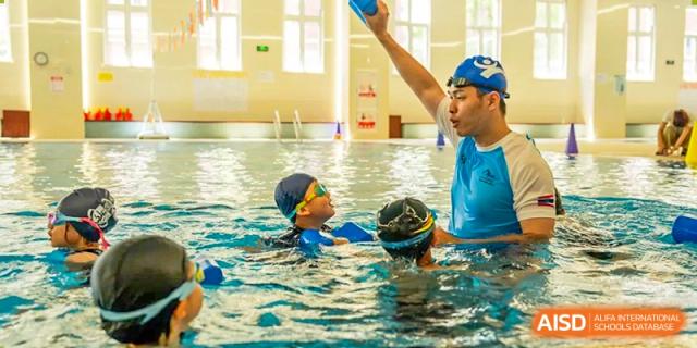 An image showing a teacher instructing a young student in a swimming pool at Wellington College International Shanghai.