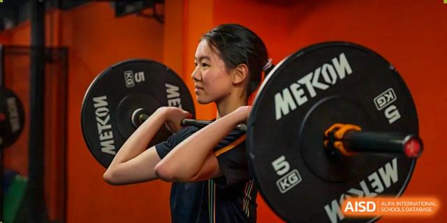 An image showing a female student lifting weights in a gymnasium at Wellington College International Shanghai.