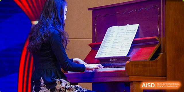 A close-up of a student playing the piano from sheet music set on the music stand at Wuhan Aoxin Elite School.