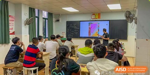 Students from Wuhan Hongshan High School International Department listening to a lesson with a colorful presentation on an interactive screen.