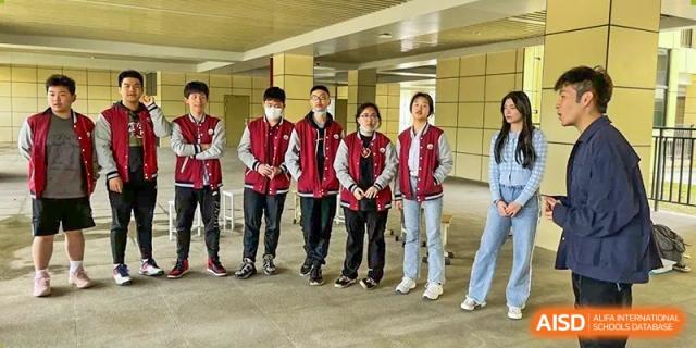 A group of students from Wuhan Hongshan High School International Department in matching school jackets posing outdoors.