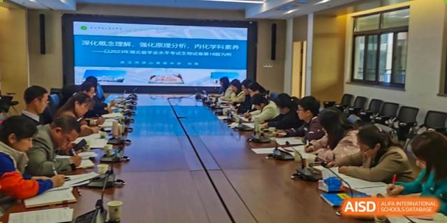 A meeting or large class of students from Wuhan Hongshan High School International Department seated around a long, reflective conference table.