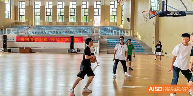 Students playing basketball on an indoor court at Wuhan Hongshan High School International Department.