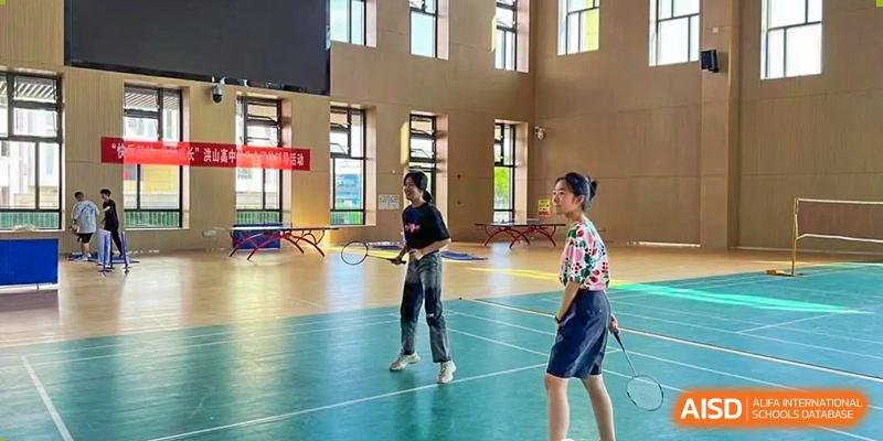 Two female students on an indoor court or gym floor at Wuhan Hongshan High School International Department.